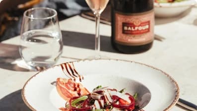 A plated dish beside a bottle of Balfour wine on a sunlit table