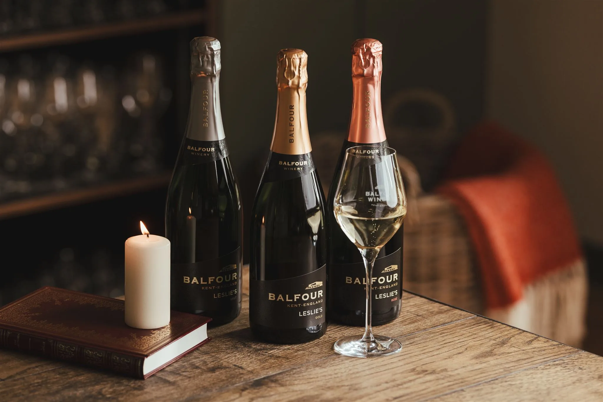 Balfour bottles and a glass beside a candle on a dark table